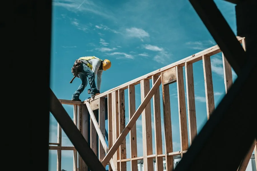 Worker on timber framing against blue sky